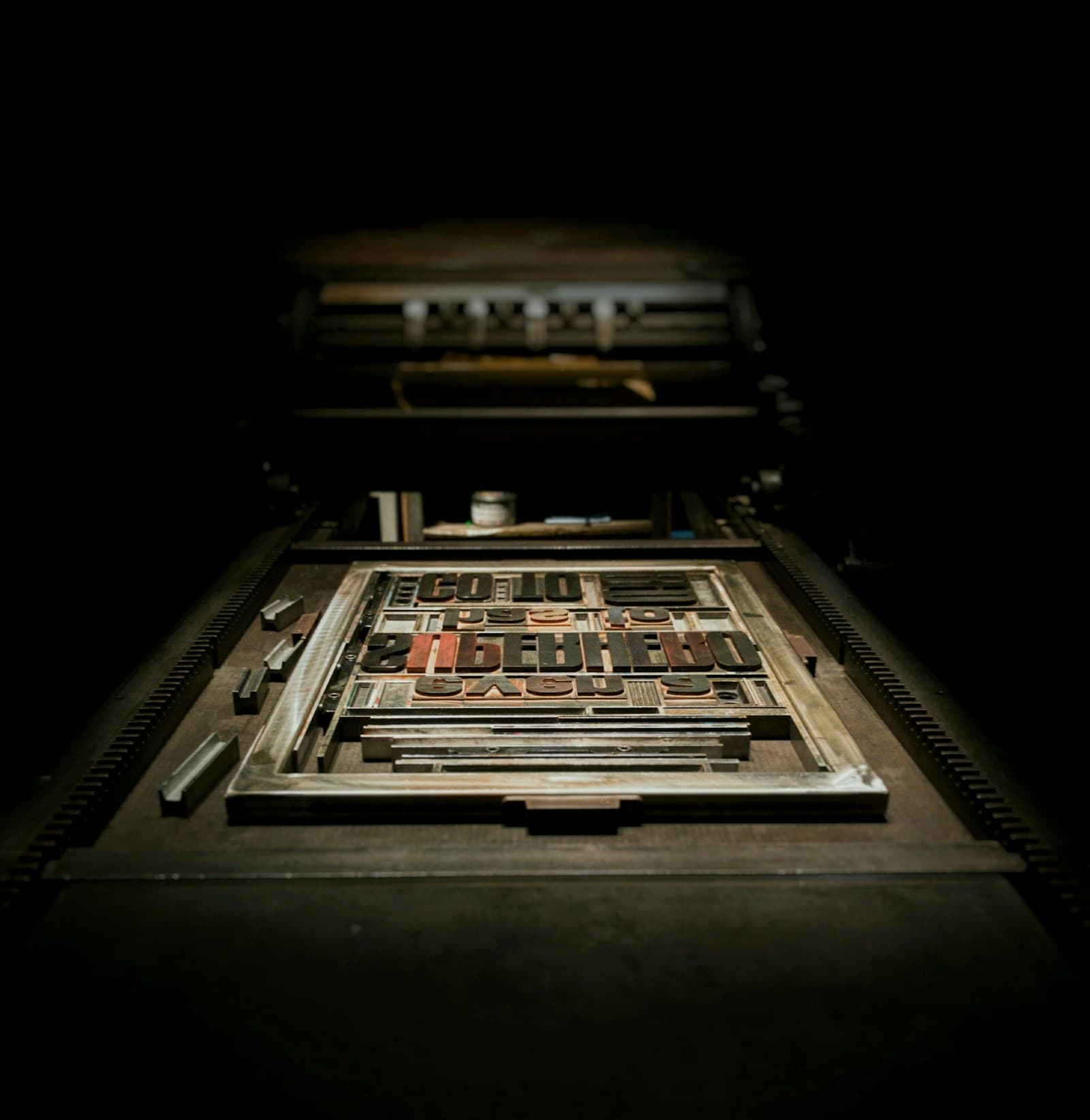Wooden letterpress type locked into a printing press bed